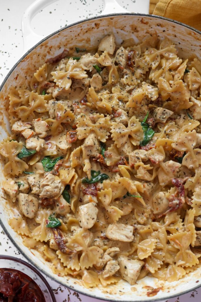 A cast iron skillet filled with creamy Tuscan chicken pasta, featuring sun-dried tomatoes, spinach, and tender chicken in a rich sauce.