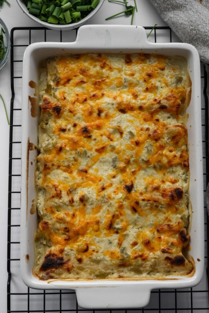 white casserole dish filled with chicken enchiladas and sour cream sauce