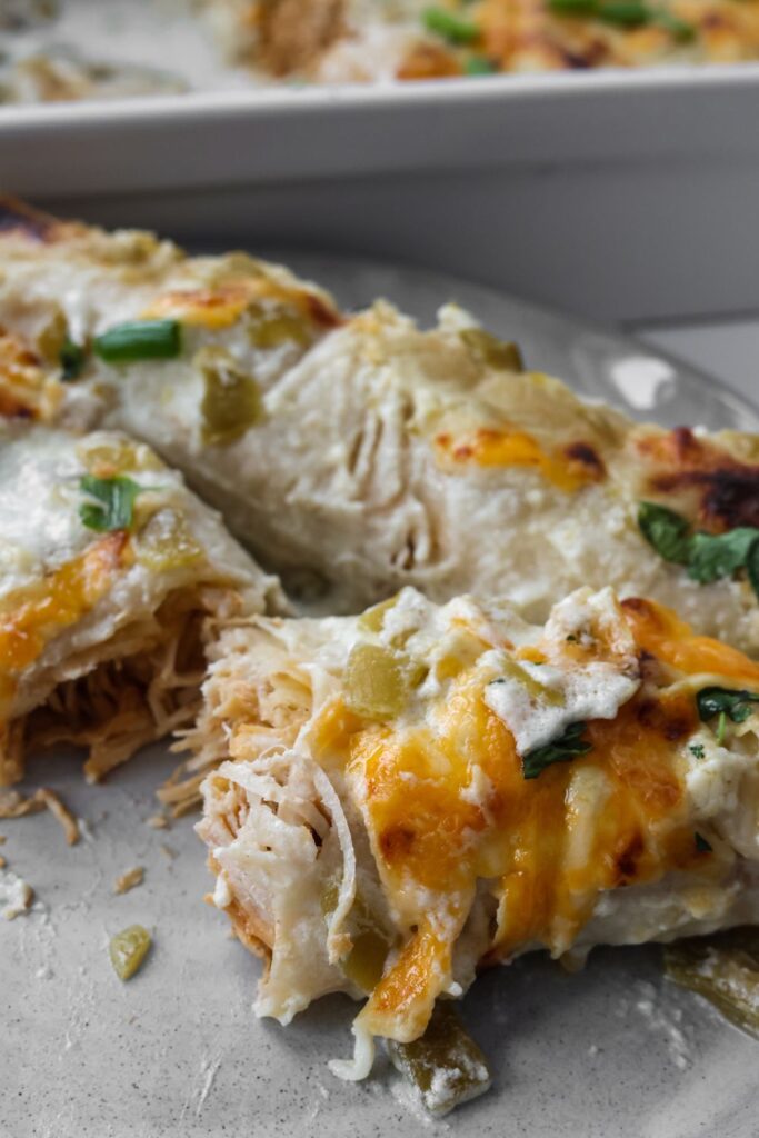 two chicken enchiladas on a plate with one of them cut in half so you can see the chicken 