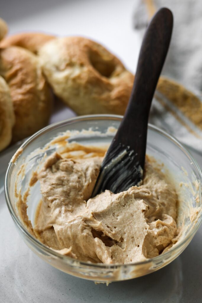 A bowl of homemade brown sugar cinnamon cream cheese with a spoon resting inside, ready to be spread.