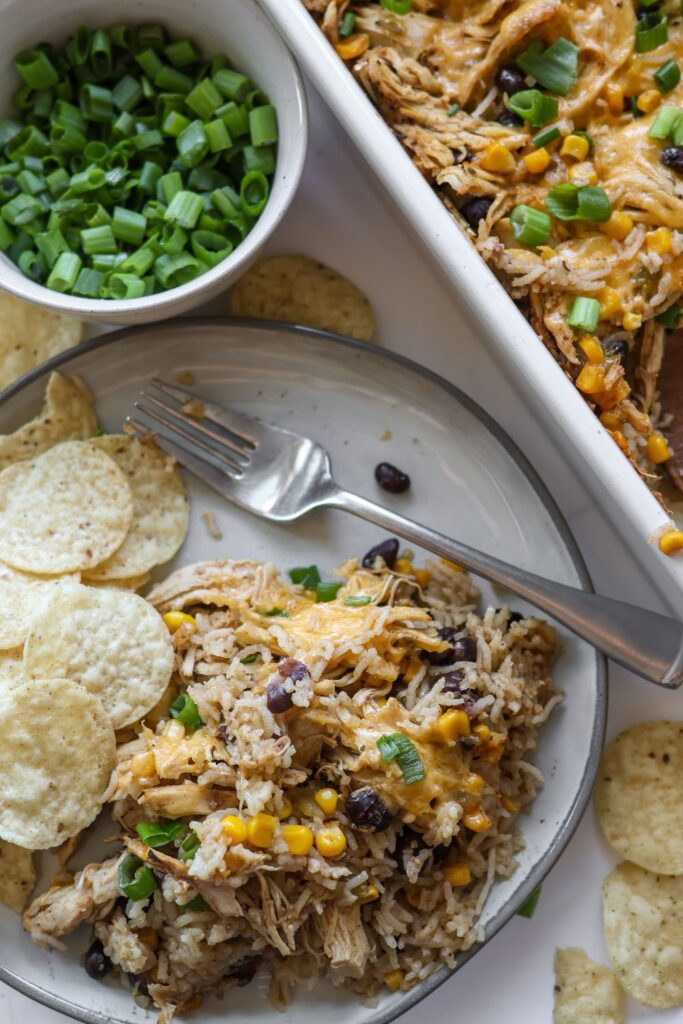 A plate of Chicken Burrito Casserole with a fork, showcasing the cheesy, flavorful layers of rice, chicken, black beans, and corn.