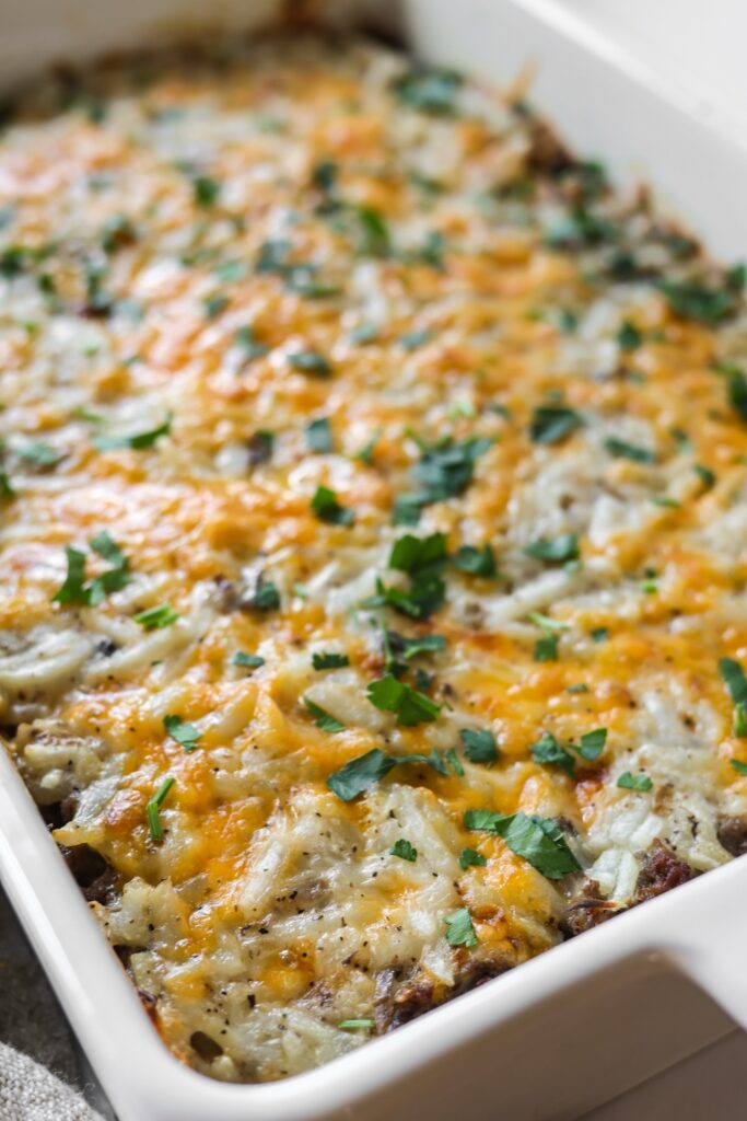 A golden, baked hamburger hashbrown casserole in a casserole dish