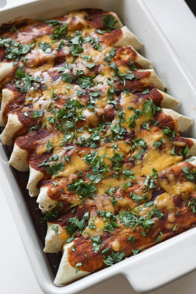 9 rolled up baked enchiladas in a casserole dish